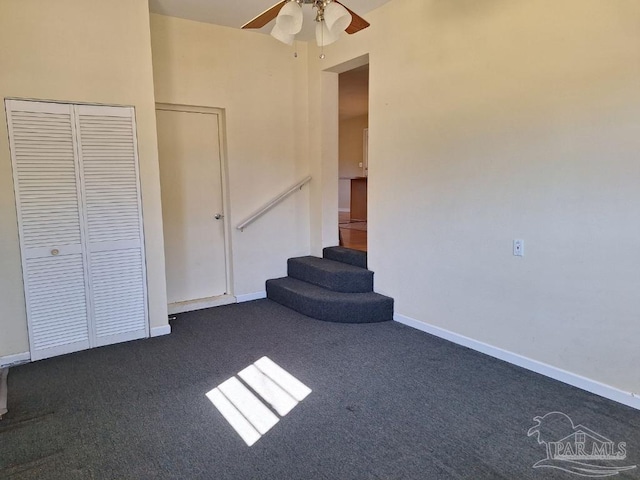 interior space featuring dark colored carpet, ceiling fan, and a closet