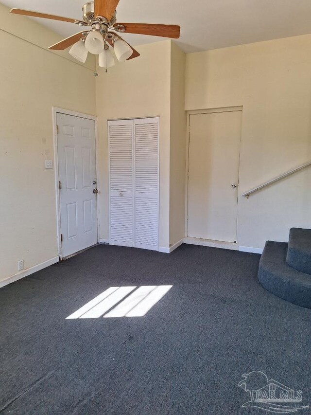 interior space featuring ceiling fan, a closet, and dark colored carpet