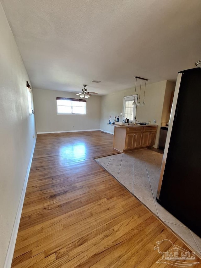 unfurnished living room featuring ceiling fan, light hardwood / wood-style flooring, and a healthy amount of sunlight