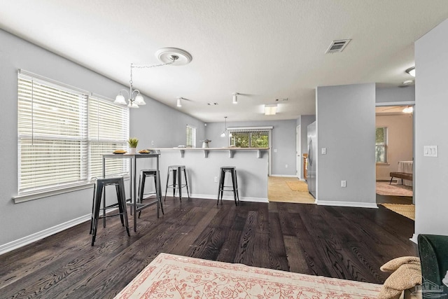 kitchen with dark hardwood / wood-style flooring, a wealth of natural light, stainless steel refrigerator, and kitchen peninsula