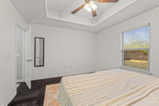 bedroom with a raised ceiling, dark hardwood / wood-style floors, and ceiling fan