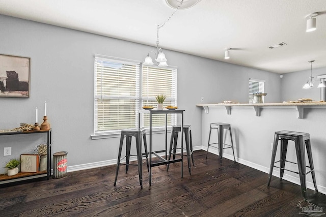 dining space with dark hardwood / wood-style flooring, a notable chandelier, and plenty of natural light