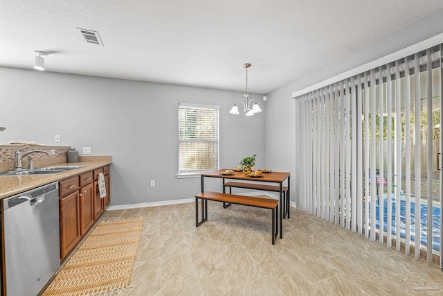 kitchen featuring sink, dishwasher, an inviting chandelier, a textured ceiling, and decorative light fixtures