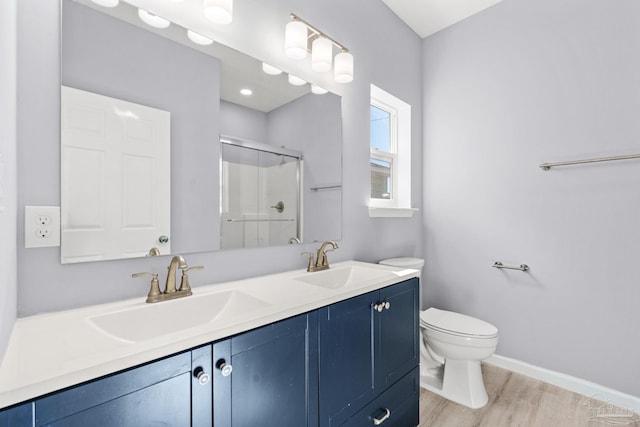 bathroom featuring a sink, wood finished floors, toilet, and a stall shower