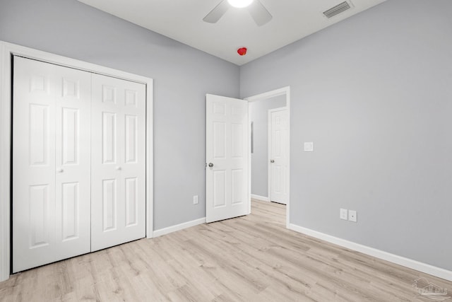 unfurnished bedroom featuring wood finished floors, visible vents, baseboards, ceiling fan, and a closet