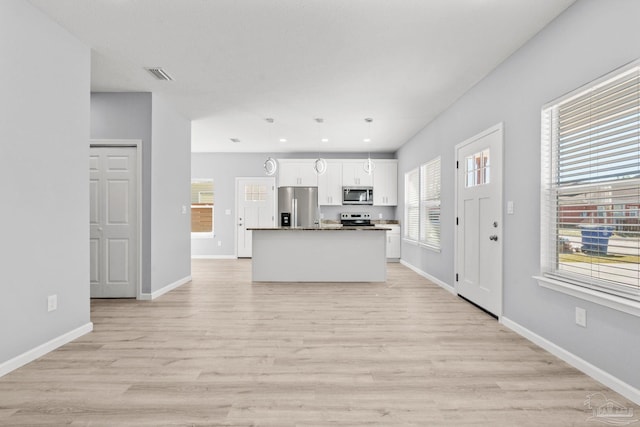 kitchen with visible vents, pendant lighting, light wood-style flooring, appliances with stainless steel finishes, and white cabinets