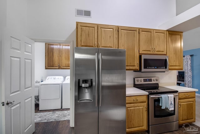 kitchen featuring stainless steel appliances, dark wood-type flooring, and washer and dryer