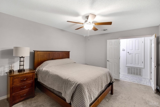 bedroom featuring ceiling fan, a textured ceiling, and light carpet