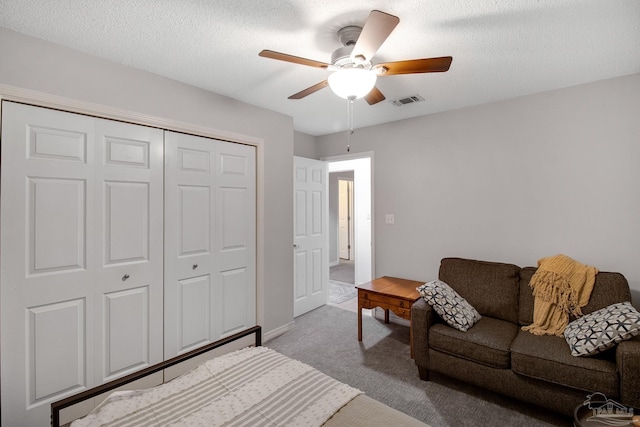 carpeted bedroom with ceiling fan, a textured ceiling, and a closet