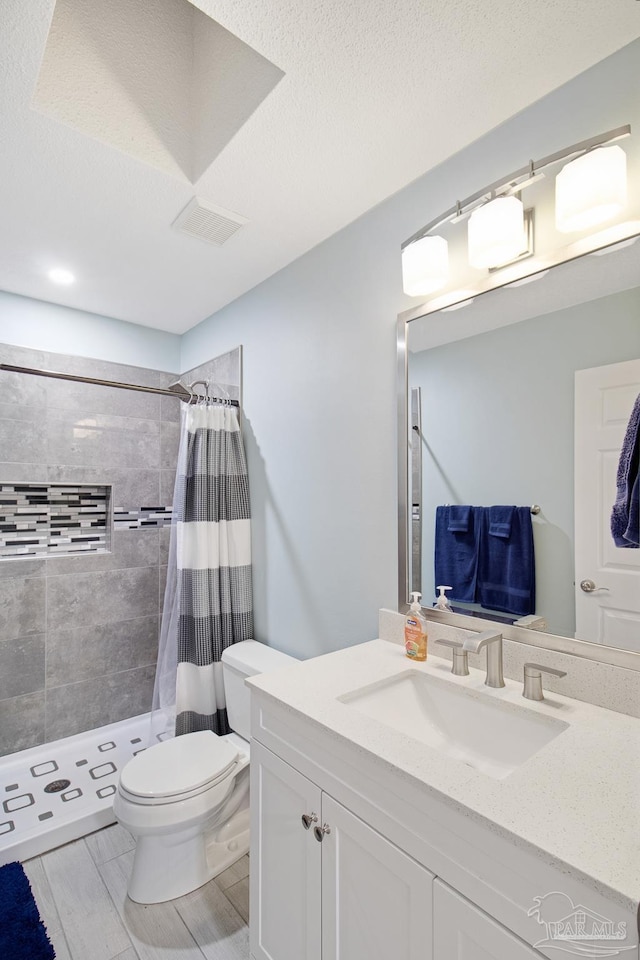 bathroom featuring a shower with curtain, vanity, toilet, and a textured ceiling