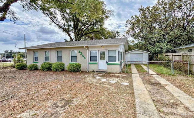 bungalow-style house with entry steps, a garage, an outdoor structure, fence, and concrete driveway