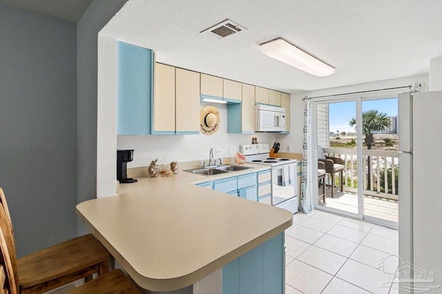1440 Paradise Point Dr Unit 13, Navarre Beach, FL 32566 - kitchen with white appliances, light countertops, a peninsula, light tile patterned floors, and a breakfast bar area