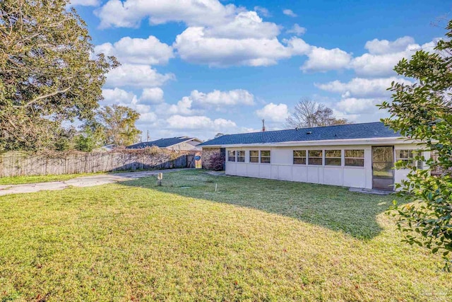 back of house with stucco siding, a lawn, and fence