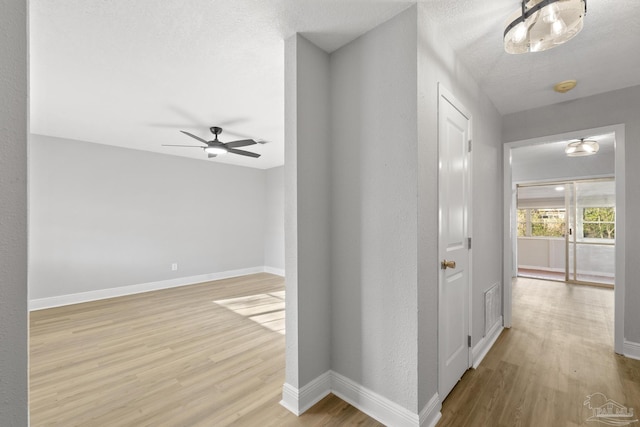 corridor featuring wood finished floors, baseboards, and a textured ceiling