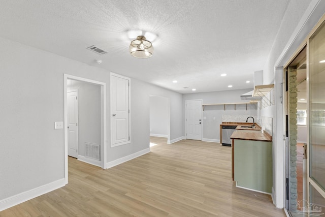 unfurnished living room featuring light wood-style flooring, baseboards, visible vents, and a sink