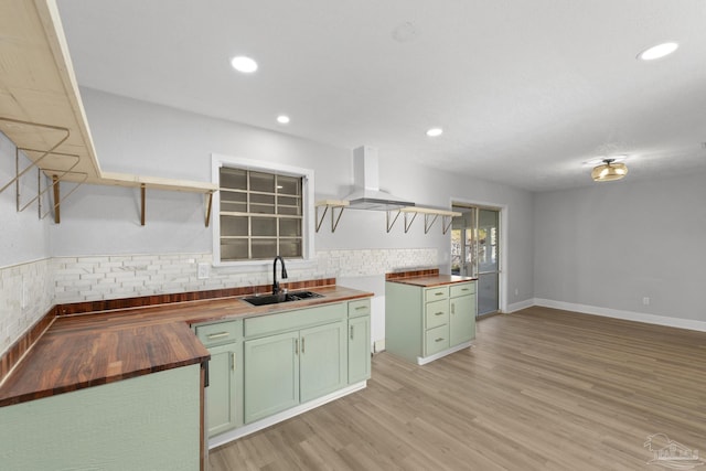 kitchen featuring open shelves, green cabinetry, light wood-type flooring, wood counters, and a sink