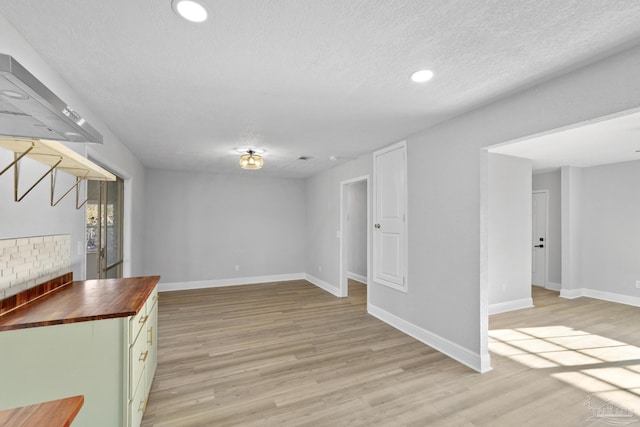 unfurnished living room featuring baseboards, a textured ceiling, light wood-style flooring, and a fireplace