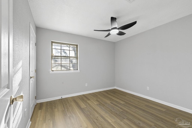 empty room with baseboards, wood finished floors, and a ceiling fan