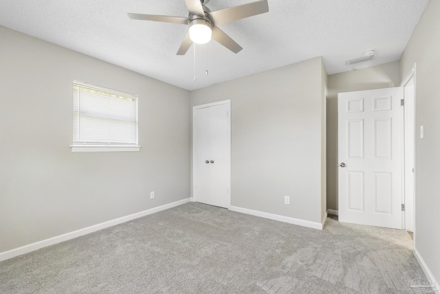 unfurnished bedroom with a textured ceiling, ceiling fan, and light carpet