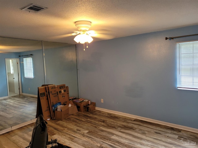 unfurnished room featuring hardwood / wood-style floors, ceiling fan, and a textured ceiling