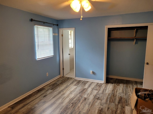unfurnished bedroom featuring ceiling fan, a closet, and hardwood / wood-style flooring