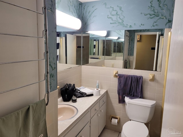 bathroom featuring vanity, toilet, and tile walls
