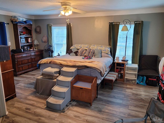 bedroom featuring hardwood / wood-style floors, ceiling fan, and a textured ceiling