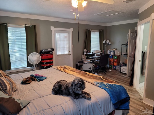 bedroom featuring multiple windows, a textured ceiling, hardwood / wood-style flooring, and ceiling fan