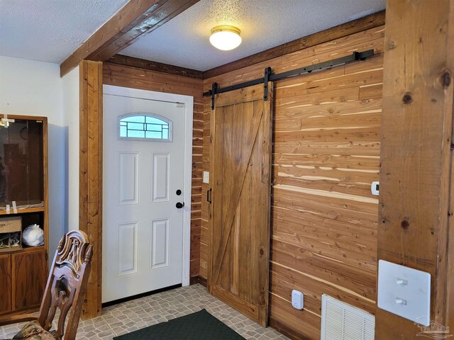 entrance foyer with wood walls, a barn door, and a textured ceiling