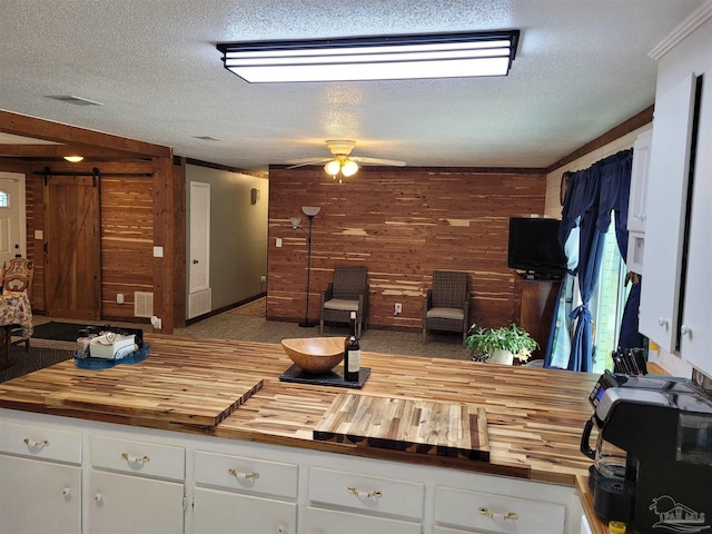 kitchen featuring butcher block countertops, a barn door, and white cabinetry