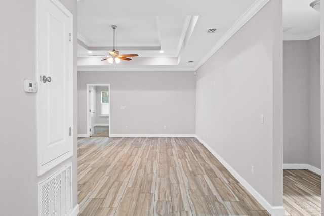 unfurnished room with ceiling fan, light hardwood / wood-style floors, ornamental molding, and a tray ceiling