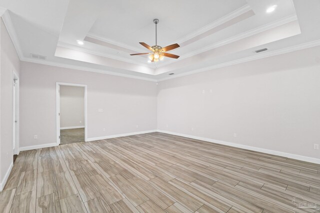 unfurnished room with light wood-type flooring, a raised ceiling, ceiling fan, and ornamental molding