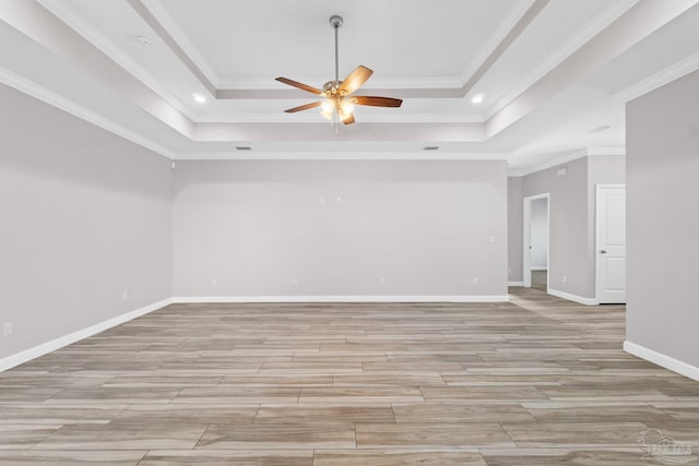 empty room featuring light hardwood / wood-style floors, a raised ceiling, ceiling fan, and ornamental molding