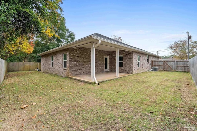 rear view of property with a patio area, a yard, and central AC