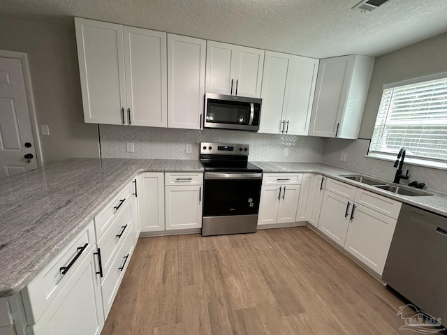 kitchen with light wood-style floors, white cabinetry, appliances with stainless steel finishes, and a sink