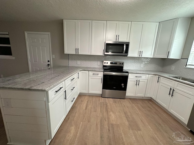 kitchen featuring a peninsula, white cabinets, and stainless steel appliances