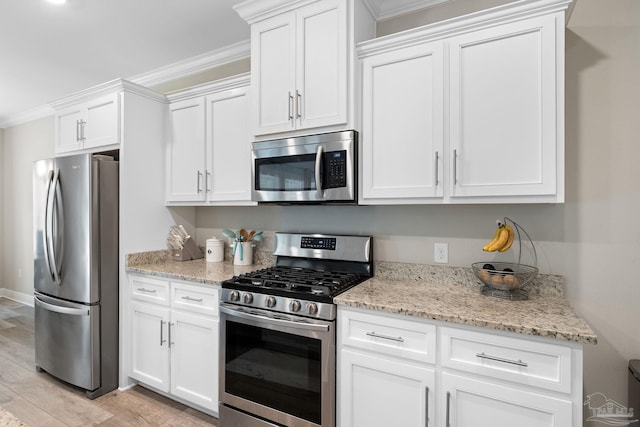 1604 Cadence Loop, Cantonment, FL 32533 - kitchen with appliances with stainless steel finishes, white cabinetry, light stone countertops, ornamental molding, and light wood-style flooring