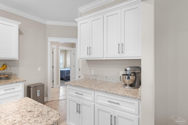 1604 Cadence Loop, Cantonment, FL 32533 - kitchen featuring ornamental molding, white cabinetry, light wood-style floors, light stone countertops, and baseboards