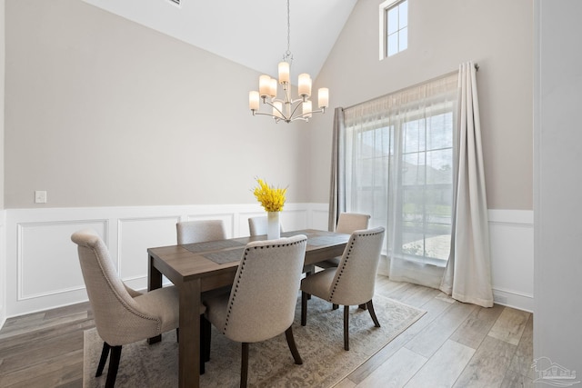 1604 Cadence Loop, Cantonment, FL 32533 - dining room with a chandelier, wainscoting, light wood finished floors, high vaulted ceiling, and a decorative wall