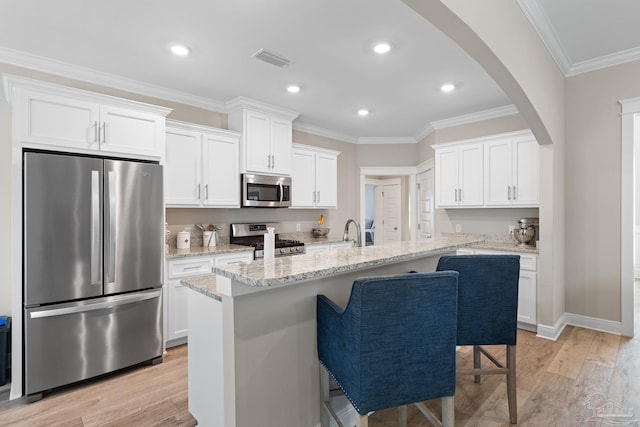 1604 Cadence Loop, Cantonment, FL 32533 - kitchen with stainless steel appliances, arched walkways, white cabinets, light wood-style flooring, and ornamental molding