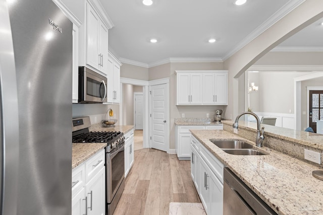 1604 Cadence Loop, Cantonment, FL 32533 - kitchen with stainless steel appliances, a sink, ornamental molding, white cabinetry, and light wood finished floors