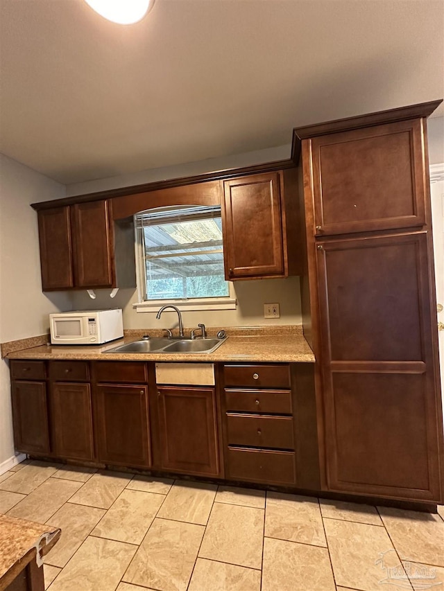 kitchen featuring sink, dark brown cabinets, and light tile patterned floors