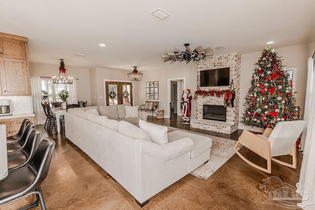 living room with ceiling fan with notable chandelier and a stone fireplace