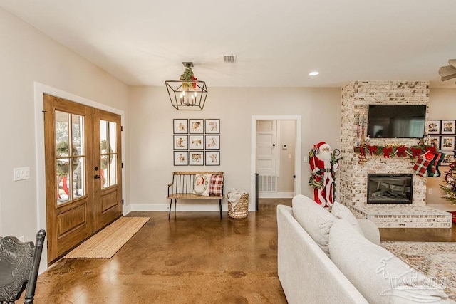 entryway with french doors, concrete floors, a brick fireplace, and a notable chandelier