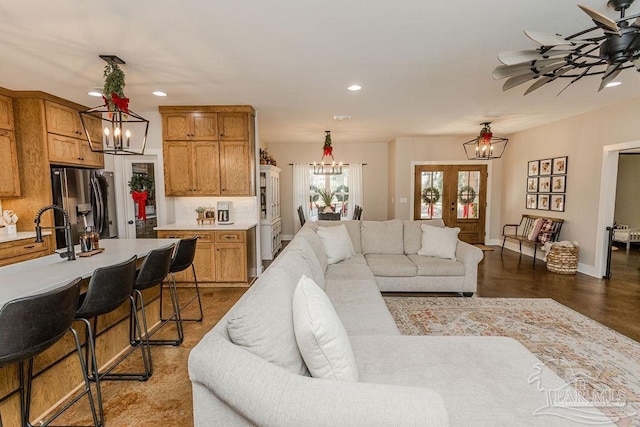 living room featuring ceiling fan with notable chandelier and sink