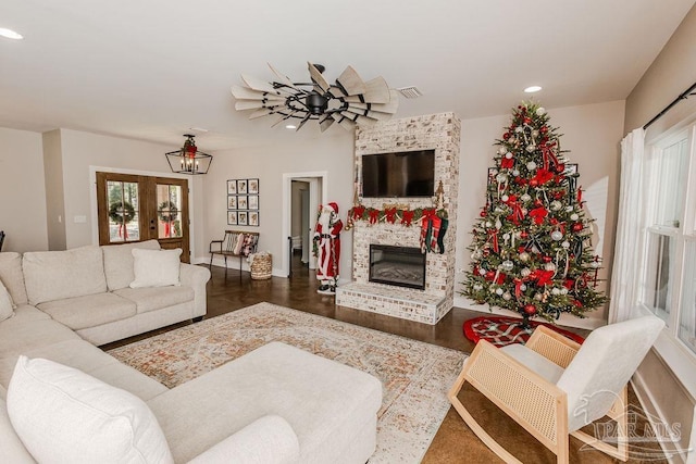 living room featuring a fireplace, wood-type flooring, and an inviting chandelier