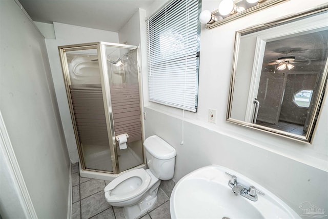 bathroom featuring ceiling fan, a shower with door, sink, tile patterned flooring, and toilet