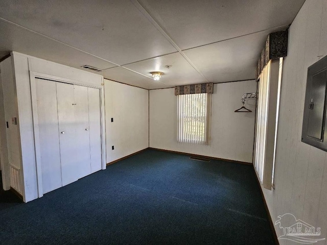 unfurnished bedroom featuring electric panel, a closet, and dark colored carpet