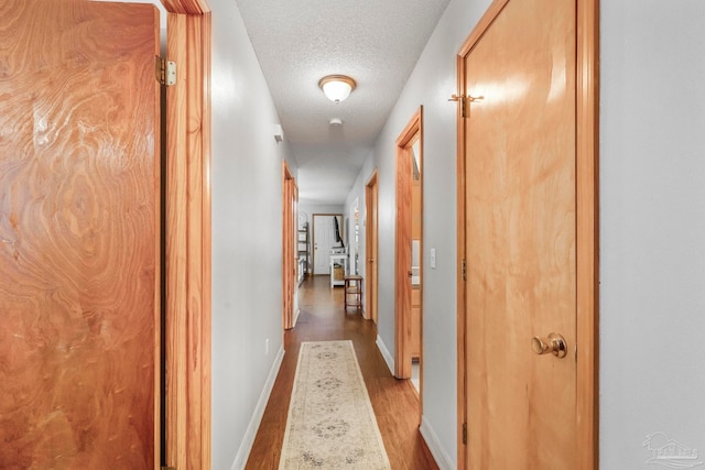 hallway with light hardwood / wood-style floors and a textured ceiling