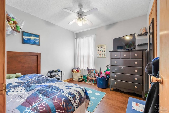 bedroom with ceiling fan, a textured ceiling, and light hardwood / wood-style flooring